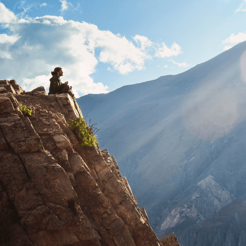 Person sitting on a mountain cliff
